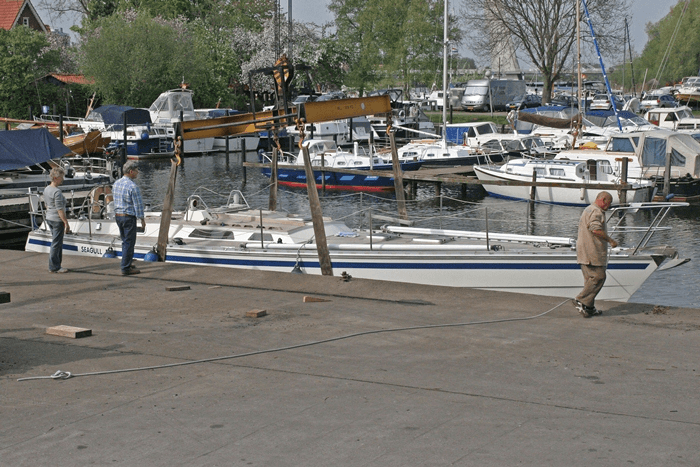 Een zeilboot wordt met de botenkraan uit het water gehaald bij Jachthaven De Hanze